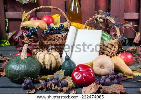 Autumn and Thanksgiving concept. Seasonal fruit and pumpkins in basket on wood background with open old book to place your text.