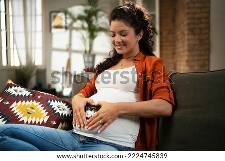 Pregnant woman with ultrasound photo. Beautiful pregnant woman enjoy at home