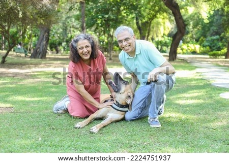 Happy indian senior couple playing with dog in summer park. Retirement life, retired people enjoying life in garden. having fun. Royalty-Free Stock Photo #2224751937