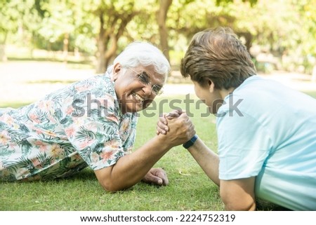 Senior Indian Couple Arm Wrestling Game With Each Other At Park Outdoor. Retirement life. Playful elderly people.