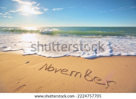 November word on sea sand. Nature cpmposition.