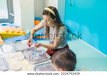 Caucasian pretty teacher helping kids to start painting in the kindergarten. High quality photo
