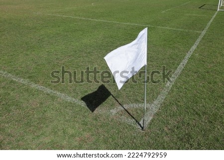 Corner flag on a soccer field. Closeup of white corner flag with shadow on green soccer field with copy space and selective focus.