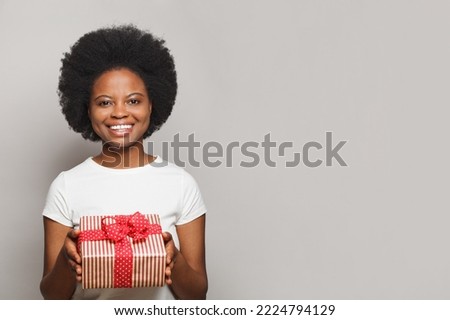 Pretty friendly positive smiling woman with red gift box looking at camera on white background