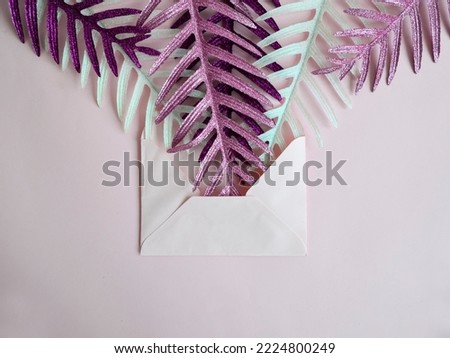 Christmas composition. Pink, purple and white Christmas decoration in envelope against pink table background. Flat lay, top view, copy space. New Year sale card. Pink Christmas.
