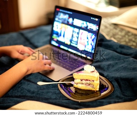 A business person eating delicious marble pastry food while working from home. Attractive person feeling happy and enjoy, use laptop computer study learn online and eat pastry in house.