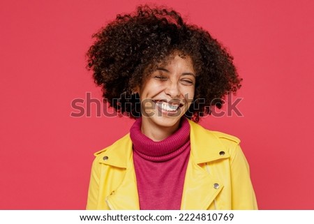 Laughing bright happy fun young curly black latin woman 20s years old wears yellow jacket keep eyes closed smiling isolated on plain red background studio portrait. People emotions lifestyle concept Royalty-Free Stock Photo #2224810769