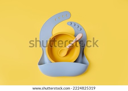 Blue silicone baby bib and and bowl. Serving baby. First baby accessories for dinner.  Top view, flat lay Royalty-Free Stock Photo #2224825319