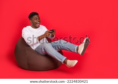 Full body portrait of excited crazy person sitting bag play videogames isolated on red color background