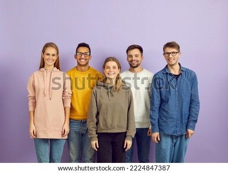 Group portrait of smiling multiethnic young people pose on violet studio background show unity and leadership. Happy diverse multiracial students or colleagues for team picture.