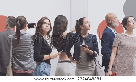 Visitors at the art gallery, they are looking at paintings and taking pictures: contemporary art exhibition concept