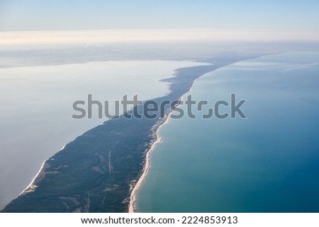 Aerial view from airplane window to Curonian spit in Kaliningrad Oblast, Russia, beautiful green forest and sandy beach on curved sand dune spit between Baltic sea. Aerial view to Kurshskaya kosa Royalty-Free Stock Photo #2224853913