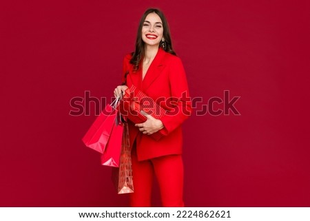 attractive woman in red suit with shopping bags sale on red background happy smiling long hair stylish fashion trend black friday Royalty-Free Stock Photo #2224862621