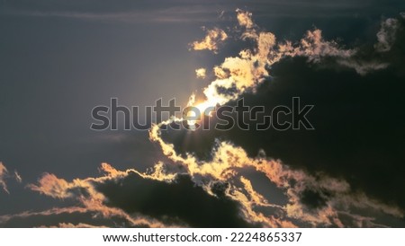 Sun partially breaking through clouds against a grey sky