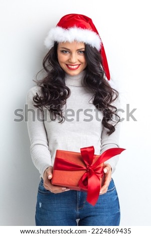 Picture of lovely casual woman in Santa hat with present box with red ribbon bow on white