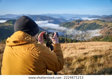 A young photographer taking picturesque photos using his cellphone. Landscape photography. Content maker. Pro photographer. The concept of travel and active lifestyle.  Time lapse on smartphone.      
