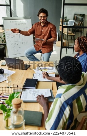 Confident coach explaining financial graph to colleagues