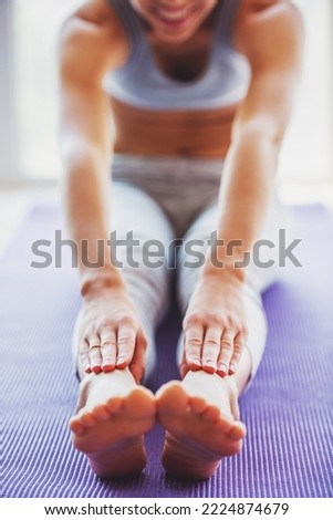 Cropped image of beautiful young woman in sports wear stretching on a yoga mat