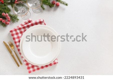 Christmas table setting with red decorations, wine glasses on white background. View from above. Copy space. Xmas festive dinner.