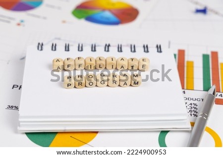 Business concept. On the charts with economic indicators are a pen, a notebook and cubes with the inscription - Affiliate program
