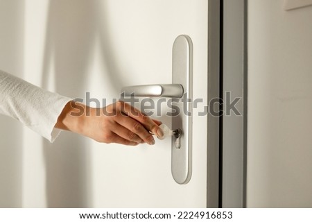 The hand puts the key in the keyhole and opens the door