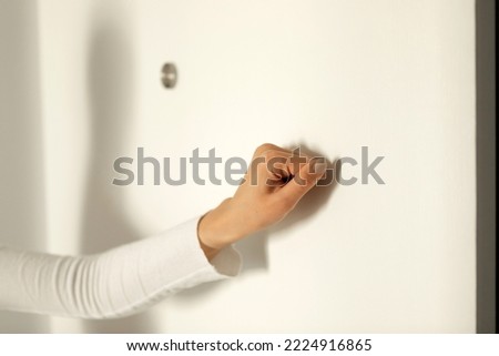 Woman's hand knocking on the door