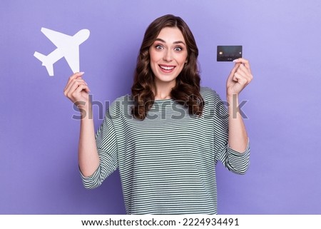 Photo of excited tourist hand hold paper card plane debit card rejoice comfort fast ticket reservation isolated on purple color background