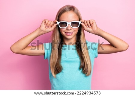 Photo of cheerful sweet small kid wear turquoise t-shirt arms dark spectacles smiling isolated pink color background