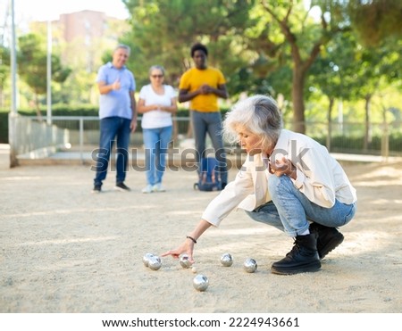Smiling mature people playing petanque on sand together Royalty-Free Stock Photo #2224943661