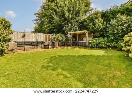 Neat paved patio with sitting area and small garden near wooden fence Royalty-Free Stock Photo #2224947229