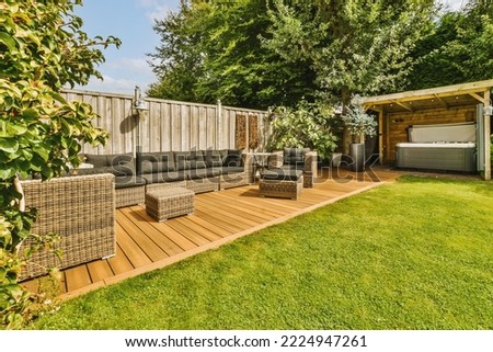 Neat paved patio with sitting area and small garden near wooden fence Royalty-Free Stock Photo #2224947261