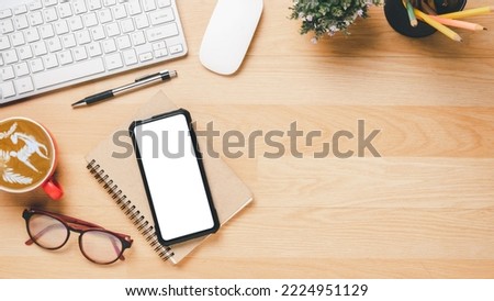Flat lay, Wooden office desk with keyboard computer,blank screen smart phone, mouse, pen, eyeglass, notebook and coffee, Top view with copy space, Mock up.