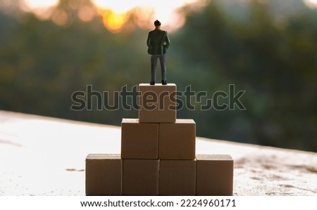 Businessman miniature with wooden block, selective focus.