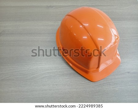 Orange safety helmet on a wooden table. Illustration of safety equipment.