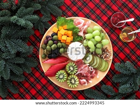 Appetizer wooden platter with variety of cheese, meats and fruits. Chrcuterie platter for christmas.   
Top view, flat lay.
