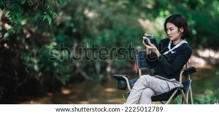 Young pretty woman use digital camera taking a photo beautiful nature while camping in forest with happiness, copy space