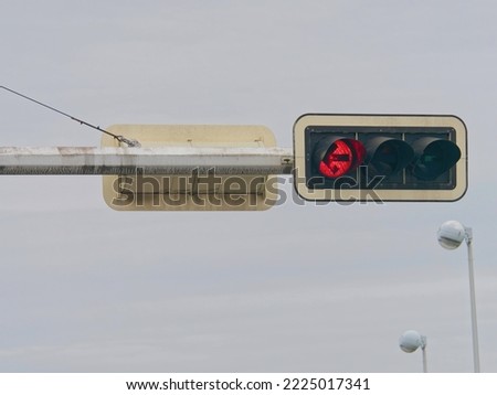 Close-up photo of a red traffic light on a metal pole with a misty sky in the background