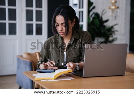 Pretty African American pretty student girl sitting at desk with laptop, diary uses calculator counts profit of her business. Remote working Brazilian young woman tired, feels fatigue. Royalty-Free Stock Photo #2225025915