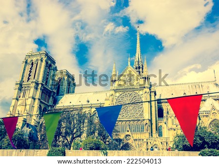 Notre Dame Cathedral in Paris and colorful flags at foreground. Selective focus on the Notre Dame Cathedral. Retro aged photo.