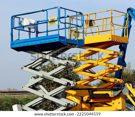 Two scissor elevators, a type of  aerial working platforms. Sky on background.  Royalty-Free Stock Photo #2225044559
