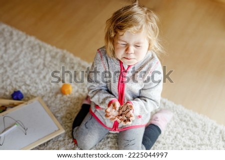 Sad crying toddler girl learning painting with felt tip pens. Little baby child drawing on hands and clothes. Angry child in hysteric crisis as parents scold with daughter for dirty hands.