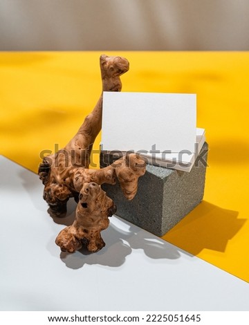 Real photo, mock up template of a business card leaning on a concrete block and a piece of wood, with floral elements to place your design.