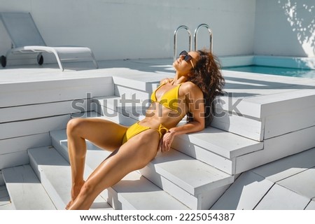 Woman sunbathing near swimming pool lying on stairs