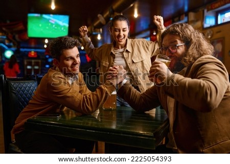 Happy friends having fun arm wrestling at sport bar