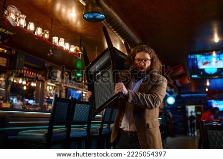Irritated man with chair in sport bar Royalty-Free Stock Photo #2225054397