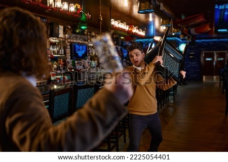 Two man hooligan football fans get in bar fight Royalty-Free Stock Photo #2225054401