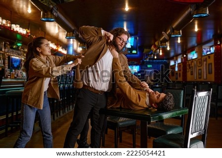 Young woman trying to separate craze mad fighting friends Royalty-Free Stock Photo #2225054421