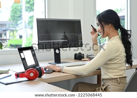 Said view of Asian woman video editor working with footage and sound in post production software