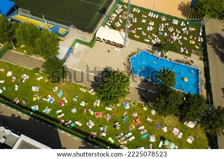 Top view of an outdoor place for people to relax where there is a swimming pool and a lot of sun beds.