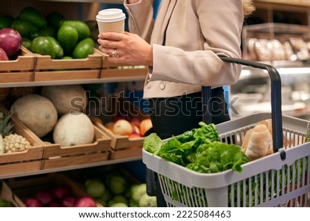 Woman, shopping and supermarket for groceries, food and ingredients in store, for meal and with coffee. Inflation, customer and client purchase vegetables, shelf with products and consumer buying.